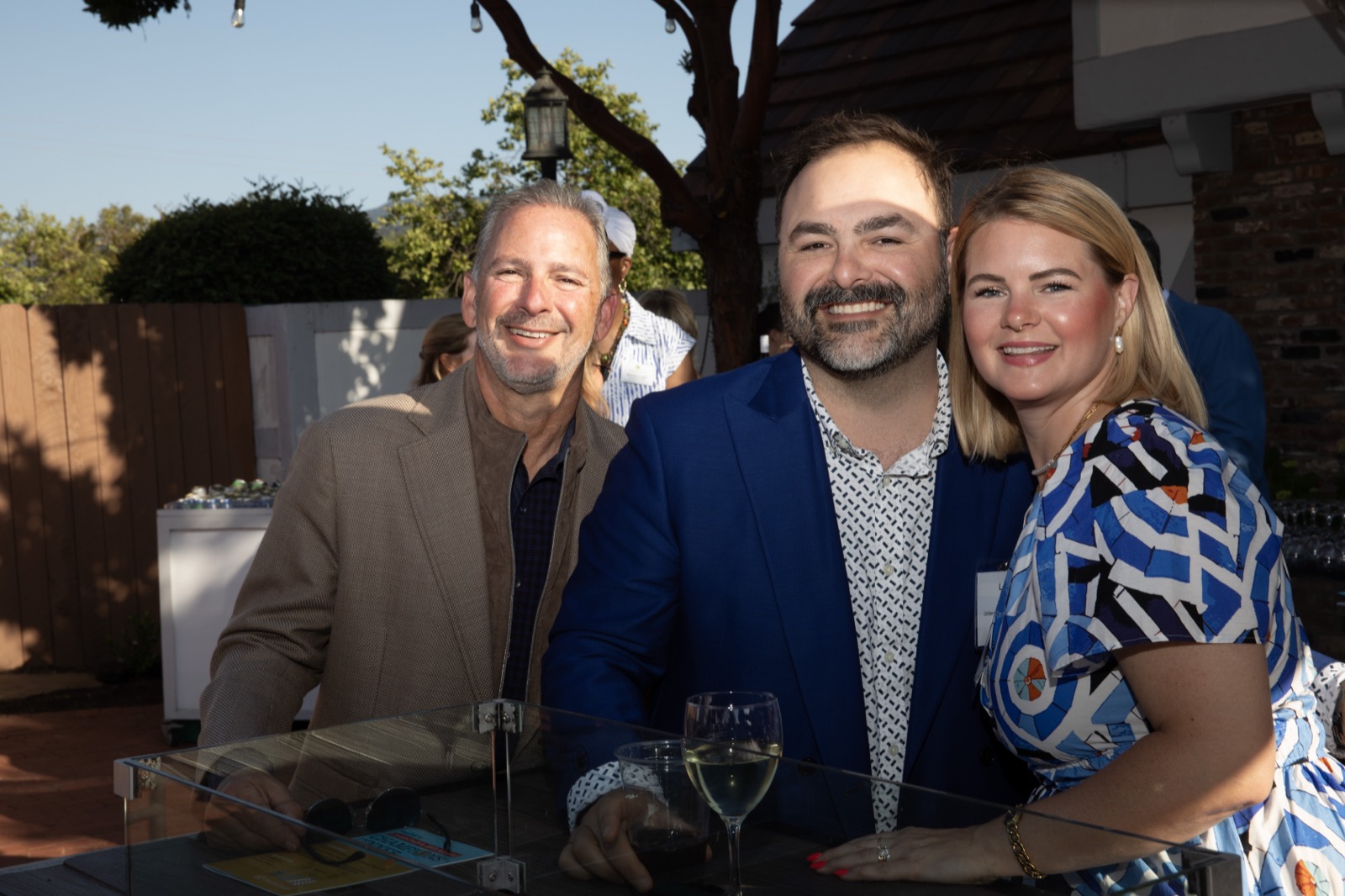 Three friends smiling with drinks at the reception