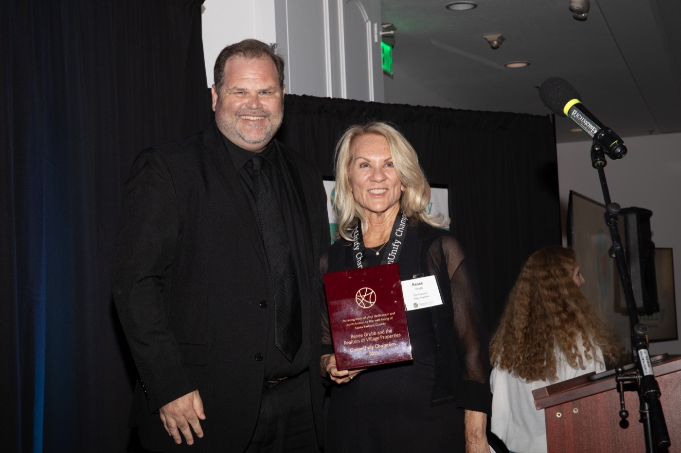 A Champions Dinner honoree holding their award plaque beside the emcee