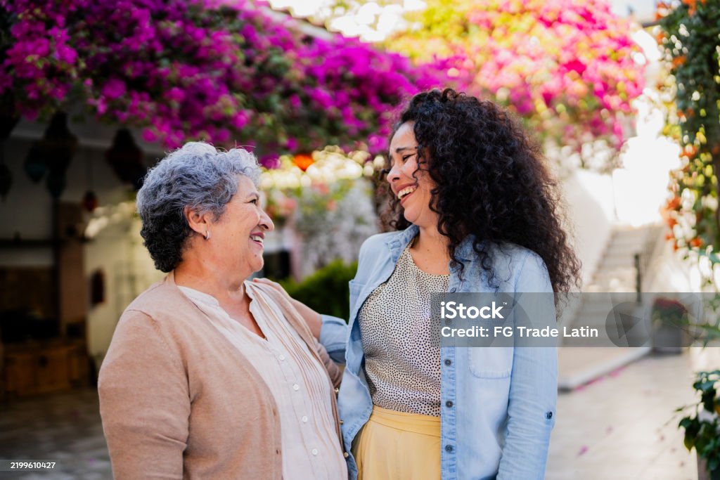 An older woman and a younger woman talking and smiling together outdoors