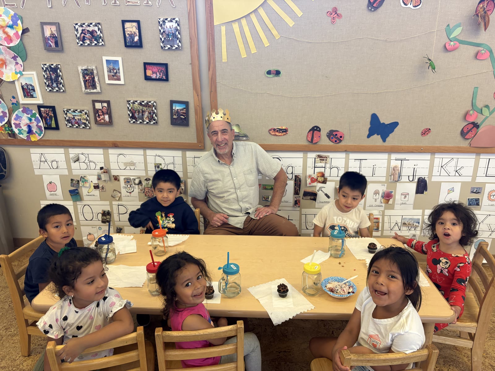 A CommUnify Head Start volunteer at a classroom table with a group of smiling preschoolers