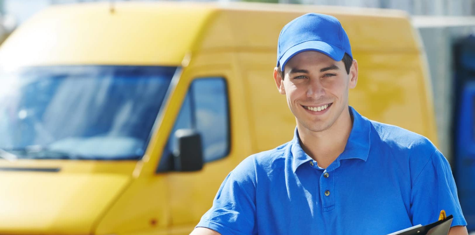 A service technician with a clipboard standing in front of his work van